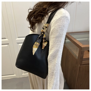 Black tote bag with vintage patterned silk scarf detail worn by model in a warm setting