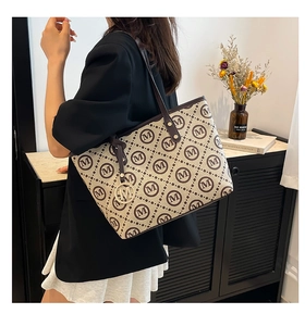 Détail du sac cabas avec motif M imprimé et breloque logo en métal doré élégante