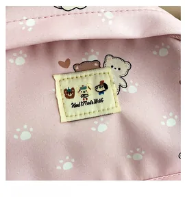Detail of pink canvas backpack with cute cartoon bear print and hand-made woven label