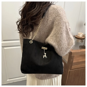 Détail du sac cabas en daim noir avec bandoulière chaîne dorée et pendentif cerf