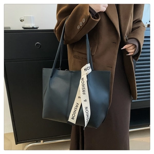 Detail of dark gray matte leather tote with beige 'FASHION' woven strap and vertical stitching