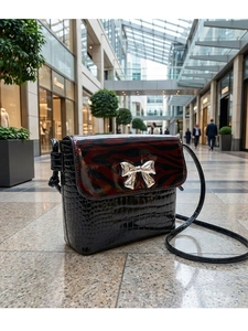 Detail of black crocodile texture bag with tiger print flap and silver bow clasp