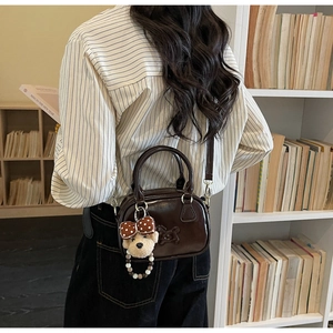 Close-up of brown vintage crossbody bag with horse motif and teddy bear charm accessory