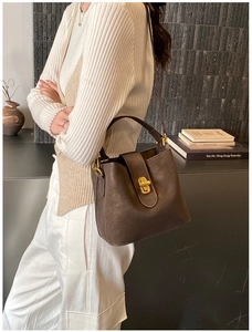Detail of dark brown matte leather bucket bag featuring a golden twist-lock closure