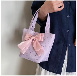 Detail of lavender star sequin handbag featuring a large soft pink silk ribbon bow decoration