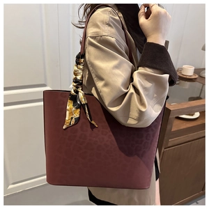 Close-up of a large burgundy leopard print tote bag with a decorative silk scarf on the handle