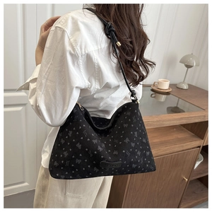 Detail of black underarm tote bag with textured butterfly pattern and fashion patch
