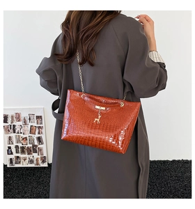 Close-up of brown crocodile pattern shoulder bag with gold chain and deer pendant