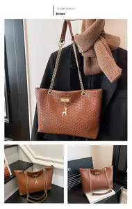 Close-up of brown woven tote bag featuring golden deer charm and chain leather strap
