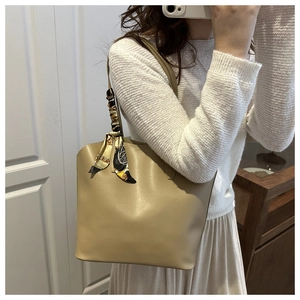 Close-up of beige tote bag with a patterned silk scarf tied on the handle for detail