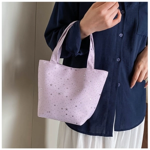 Detail of lavender canvas tote bag with silver star patterns held by a model