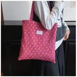 Detail of pleated tote bag featuring vibrant floral patterns and textured fabric surface