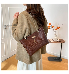 Brown crocodile pattern shoulder bag with gold deer charm and chain strap on a model