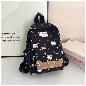 Detail of black backpack featuring white paw prints and a plush 3D bear letter patch