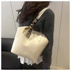 Detail of a creamy white large tote bag with decorative silk scarf on the handle