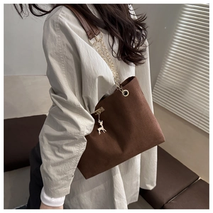Détail du sac cabas en daim marron foncé avec chaîne dorée et pendentif cerf