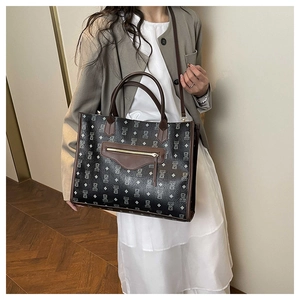 Model wearing a large black tote bag with bear patterns and brown leather handles