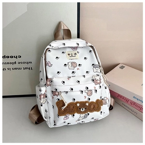 Detailed close-up of white backpack with 3D plush bear patch and cute cartoon prints