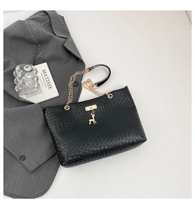 Detail of woven leather tote with golden deer charm and elegant metal chain strap