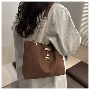 Gros plan du sac fourre-tout en toile marron avec pendentif cerf doré et bandoulière
