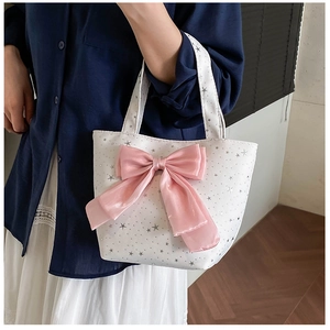 Detail of white canvas tote bag with silver star prints and large pink satin bow