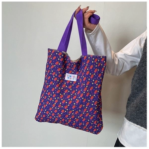 Detail of purple quilted tote bag with floral abstract patterns and brand logo label