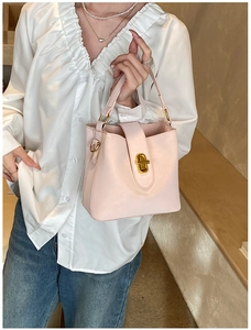 Close-up of a light pink bucket bag with a decorative gold twist-lock metal clasp detail