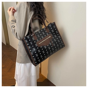 Detail of a large bear print tote bag with brown leather handles and a front zipper pocket