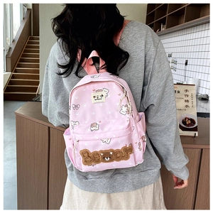 Detail of pink cartoon backpack featuring teddy bear embroidery and soft plush textures