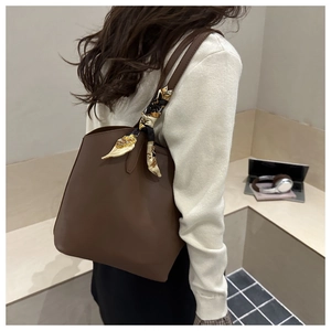 Detail of dark brown leather tote bag featuring a vintage pattern scarf on the shoulder strap