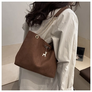 Detailed view of brown canvas tote bag with gold chain strap and deer pendant