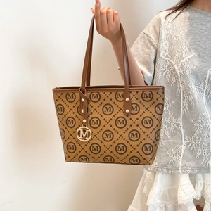 Sac cabas classique marron avec imprimé M et breloque en métal porté par un mannequin