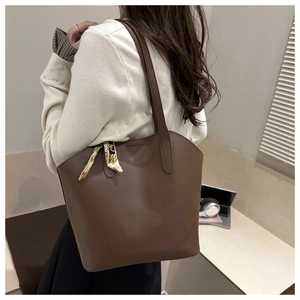 Close-up of brown tote bag showing smooth texture, reinforced stitching, and decorative scarf