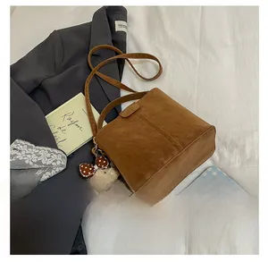 Detailansicht der braunen Wildleder-Beuteltasche mit süßem Teddybär-Anhänger und Gurt