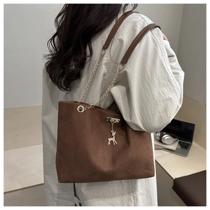 Detail of dark brown matte tote bag featuring gold chain strap and deer pendant charm
