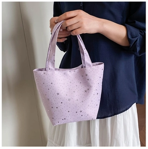 Detalle del bolso tote de lona morada con patrones de estrellas plateadas y asas dobles