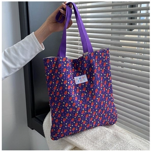 Detail of purple pleated canvas tote bag with vibrant polka dots and brand label