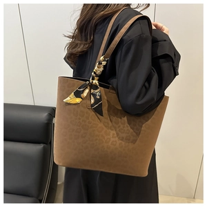 Detail of dark brown leopard suede tote bag featuring silk scarf handle on model shoulder