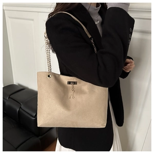 Détail du sac cabas en daim beige avec chaîne dorée et pendentif élan porté par mannequin