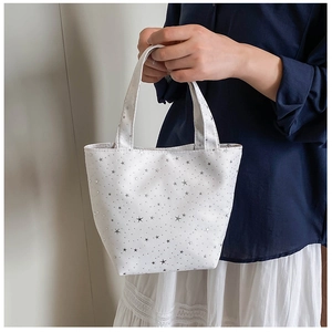 Detalle del bolso tote de lona con estampado de estrellas blancas y motivos plateados