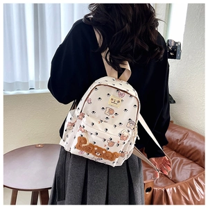 Close-up of white backpack with cartoon bears and brown plush Bear letter patch details