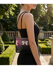 Detail of crossbody bag featuring black croc-leather and red snakeskin with bow buckle