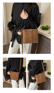 Detail of brown matte bucket bag featuring a plush bear charm and adjustable shoulder strap
