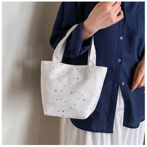 Close-up of white canvas tote bag with silver sequin stars on a lifestyle background