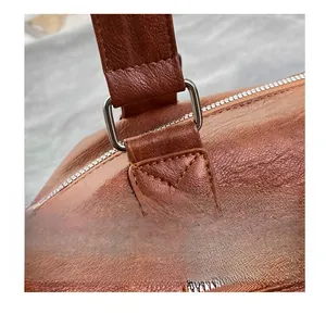 Detail of brown litchi pattern leather tote with metal ring and reinforced stitching