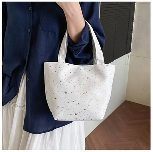 Detail of white canvas tote bag with silver star patterns and dual top handles