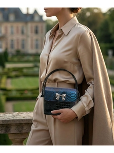 Detail of snake and crocodile texture patchwork bag with silver bow clasp
