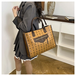 Detail of cartoon bear motif tote bag worn crossbody with professional grey blazer