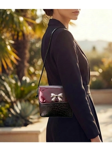 Detail of burgundy patent leather and black croc pattern crossbody bag on model