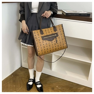 Detail of large tote bag with bear monogram pattern and dark leather handles
